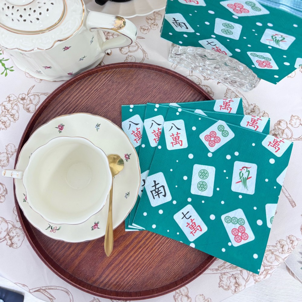 Mahjong print napkins beside a china teacup and teapot on a wooden tray